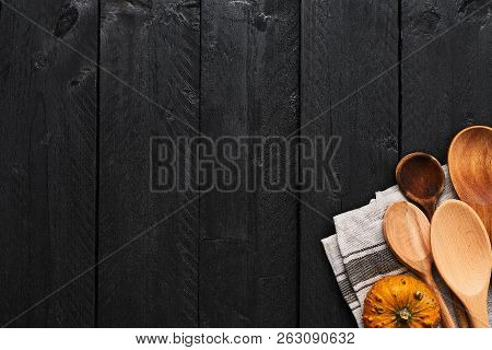 Wooden Spoons, Pumpkin And Dishtowel On Black Wooden Background With Copy Space. Top View Of Kitchen