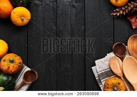 Autumn Vegetables Cooking Preparation. Top View Of Pumpkins, Wooden Spoons And Dishtowel On Black Wo