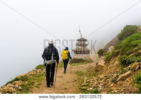 Backpackers Entering Nar Village On Foggy Trekking Path In Annapurna Conservation Area, Nepal