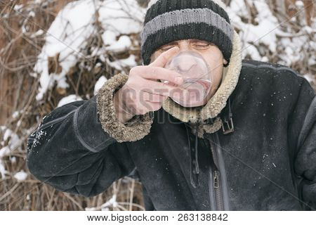 A Man Waering Warm Clothes Drinking Still Water, Frosty Scene