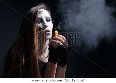 Makeup In The Style Of Halloween. A Young Girl With Long Hair With Painted Cracks On Her Face Blew O