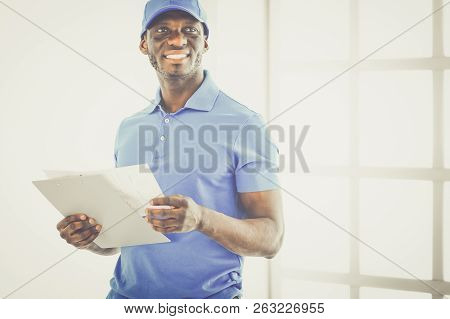Portrait Of An Handsome Happy Deliverer With Folder