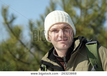 Portrait of a man with backpack in the winter pine forest