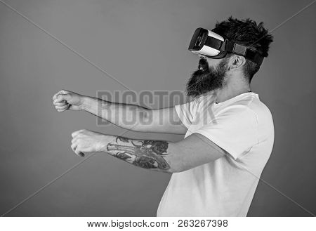 Hipster On Confident Face Driving Bike In Virtual Reality With Modern Digital Gadget. Man With Beard