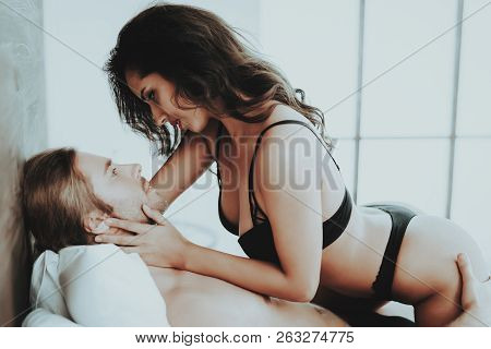 Girl Looks Into Eyes Man. Person In Black Underwear. White Linens. Woman With Sexy Man Topless. Girl
