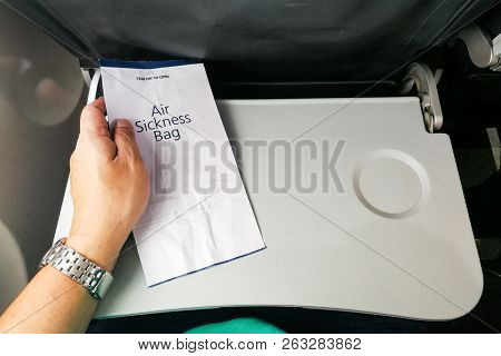 Passenger Holding Air Sickness Vomit Bag In Airplane