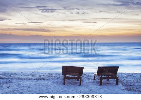 Moody Sunset Beach With Two Sunbeds And Blurred Sea
