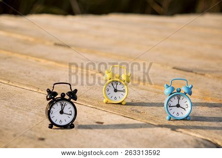 Three Small Alarm Retro Clocks On Wooden Surface. Autumn Abstract Photo.