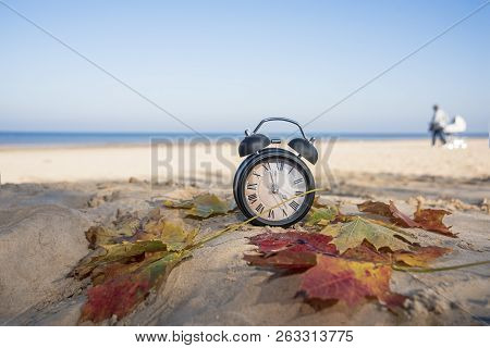 Vintage Black Alarm Clock On Autumn Leaves. Time Change Abstract Photo.
