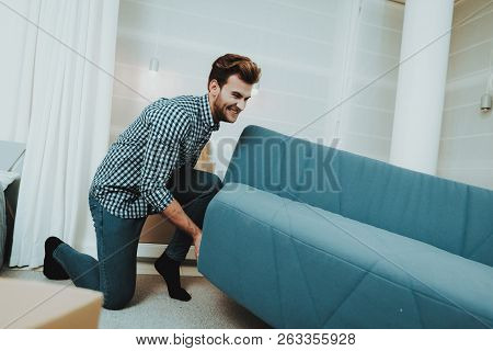 Young Male Moves A Big Sofa In The New Apartment. Reshuffle In The Room Concept. Domestic Problems. 