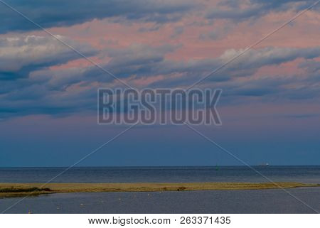 Beautiful Seascape Of Sandbar Jutting Out Into Ocean Under Blue Evening Sky With Light Pink Clouds A