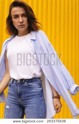 Portrait Attractive Woman On Yellow Background. She Look On Camera Pretentious Or Arrogantly.