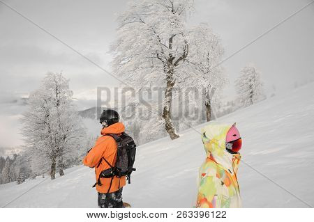 Man And Woman Snowvoarders Standing In The Mountain And Looking Into A Distance In The Popular Touri