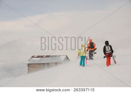 Three Snowboarders Walking With The Snowboard In The Mountain Up The Hill In The Popular Tourist Res