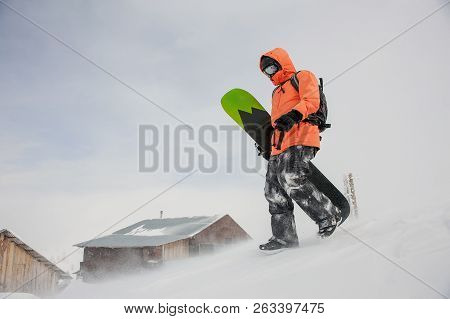 Man Walking With The Snowboard In Hands Down The Hill In The Mountain In The Popular Tourist Resort 