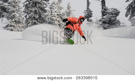 Man Running Down The Mountain Hill On The Snowboard On The Background Of Sky In The Mountain Tourist