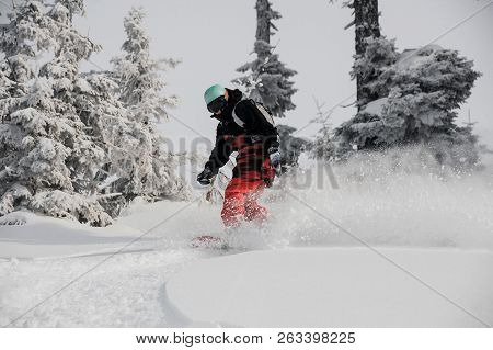 Woman Running Down The Mountain Hill On The Snowboard On The Background Of Sky And Trees In The Moun