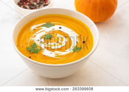 Pumpkin Soup With Cream And Pumpkin Seeds Isolated On White Background. Autumn Concept.