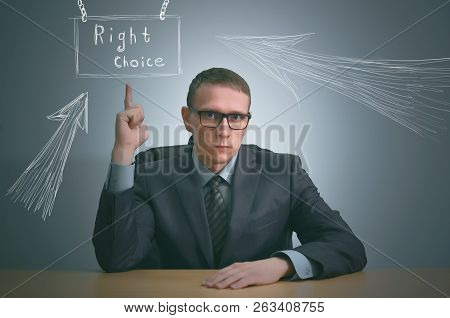 Serious Businessman Is Showing Up By His Index Finger By Sitting By The Table And Have A New Busines