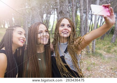 Three Young And Beautiful Girls, With Braided Hair, Taking Selfie