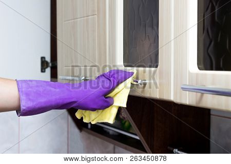 Female Hand In A Purple Glove Washes A Kitchen Cupboard With A Napkin And Cleaning Agent, Close-up, 