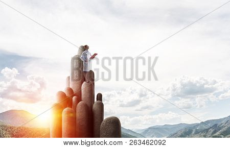 Young Female Doctor With Folder In Hands Satnding On Stone Column