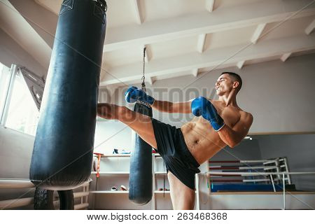 Male Boxer Workout High Kick On The Punching Bag In Gym. Sport Concept