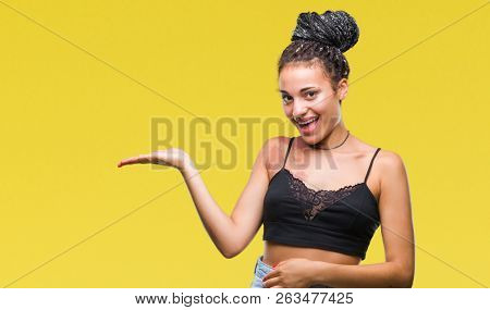 Young braided hair african american with pigmentation blemish birth mark over isolated background smiling cheerful presenting and pointing with palm of hand looking at the camera.