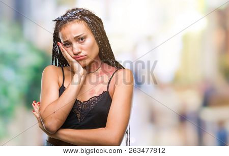 Young braided hair african american with pigmentation blemish birth mark over isolated background thinking looking tired and bored with depression problems with crossed arms.
