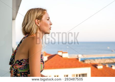 Beautiful Woman Looks At The Sea From The Buildings Balkon