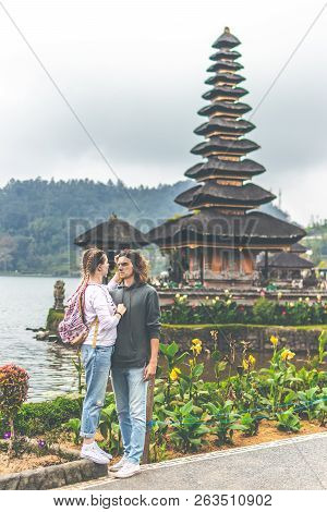 Young Romantic Couple Of Trourists On The Ulan Danu Temple Background. Bali Island.