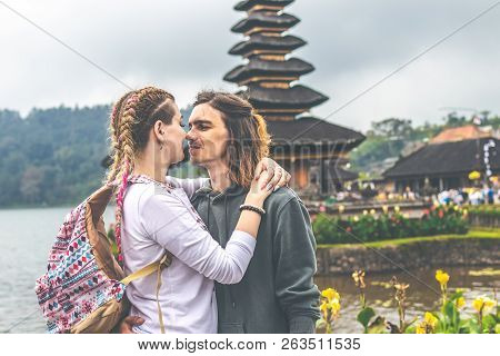 Young Romantic Couple Of Trourists On The Ulan Danu Temple Background. Bali Island.