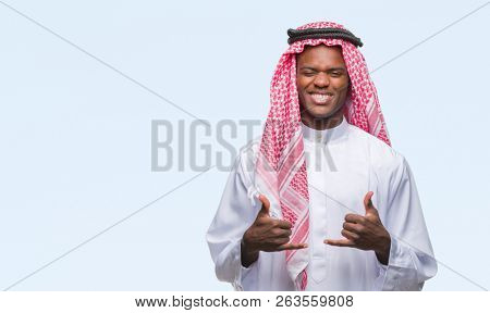Young arabic african man wearing traditional keffiyeh over isolated background success sign doing positive gesture with hand, thumbs up smiling and happy. Looking at the camera with cheerful expressio