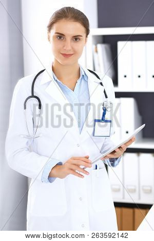 Doctor Woman In Clinic Office. Female Physician At Work Using Digital Tablet  While Standing Straigh