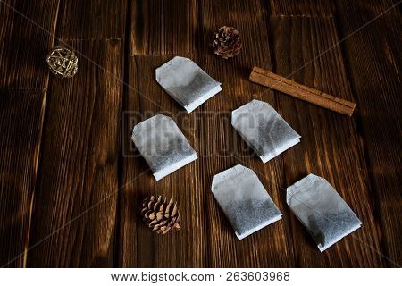 Five Tea Bags Lie On A Wooden Surface With Cinnamon And Pine Cones. Health And Nature.