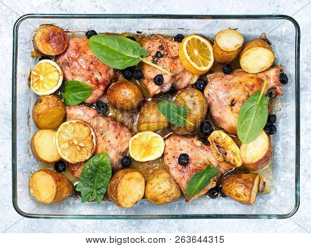 Top View Of Chicken Thighs With Potatoes, Lemon And Black Olives, Cooked In Oven On Gray Concrete Ba