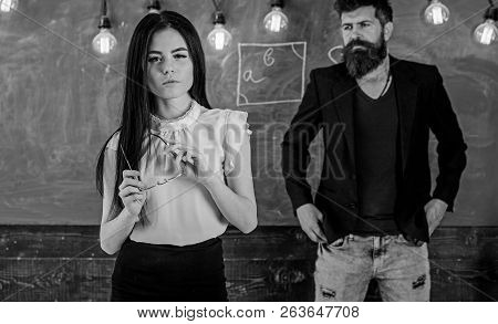 Lady Teacher And Bearded Hipster Schoolmaster Working Together In School. Man With Beard And Young L