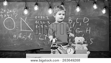 Child, Pupil On Calm Face Near Microscope. Enthusiastic Pupil Concept. Kid Boy Near Microscope In Cl