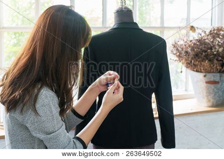 The Back Of Seamstress Young Woman Trying To Put Thread Through Needle In Modern Atelier Workshop Wi