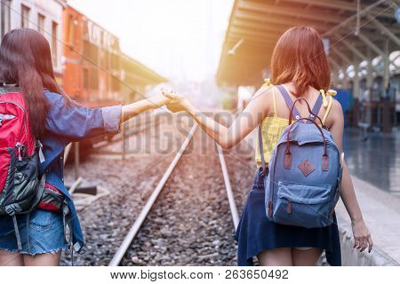 Traveler Young Woman Having Fun At Railway Station Holding Hands To Keep Balance. Attractive Friends