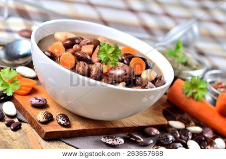 Bean Soup With Large Beans On Cutting Board, Carrots, Parsley, Marjoram, Spoon And Ladle, Towel In B