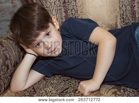 Boy With Beautiful Brown Eyes 8 Years Old Model Posing On The Couch. Boy Model