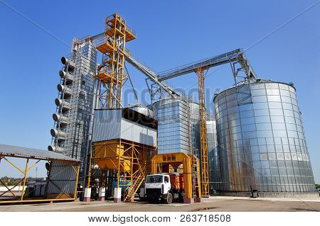 Agricultural Silo Truck Of Orange Color On The Territory Of Grain Storage In Sunny Weather.