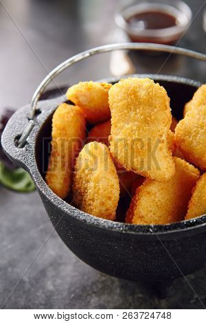 Heap of Delicious Chicken Nuggets in Metal Bowler on Dark Background. Caloric Protein Product Surrounded by Spices. Chicken Fillet in Breading