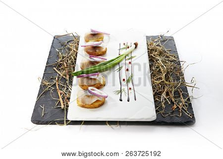 Herring Canape with Potato and Onion on Natural Rustic Background. Beautiful Creative Sea Food Design of Fish Fillet with Scallions on Dry Hay and Black Slate