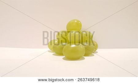 Green Grapes Stacked Into A Pyramid On White Background.