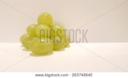 Green Grapes Stacked Into A Pyramid On White Background.