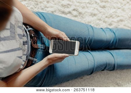 Young Woman Holding Credit Card And Using Phone Sitting On Floor. Payment.  Online Shopping Concept.