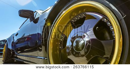 Refkective Black Car With Gold And Black Tire Rim