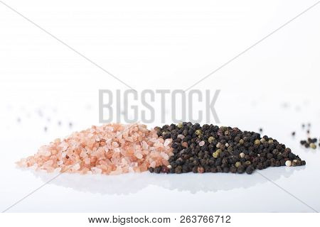 Himalayan Rock Salt And Peppercorns, Set Against A White Background.